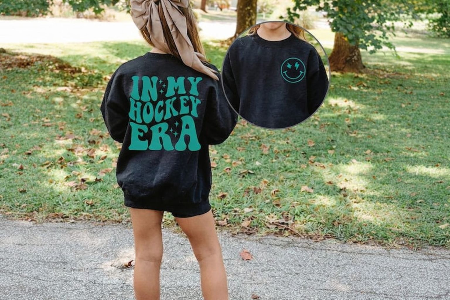 Flicka i svart hoodie med texten "IN MY HOCKEY ERA" och en leende smiley framtill.