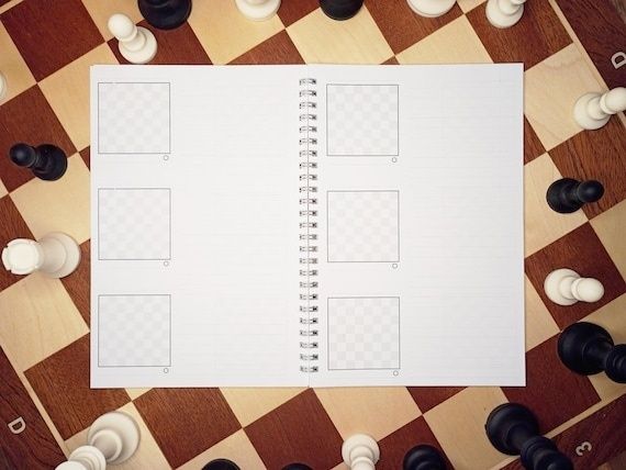 Öppet anteckningsblock på ett schackbräde med pjäser runtomkring